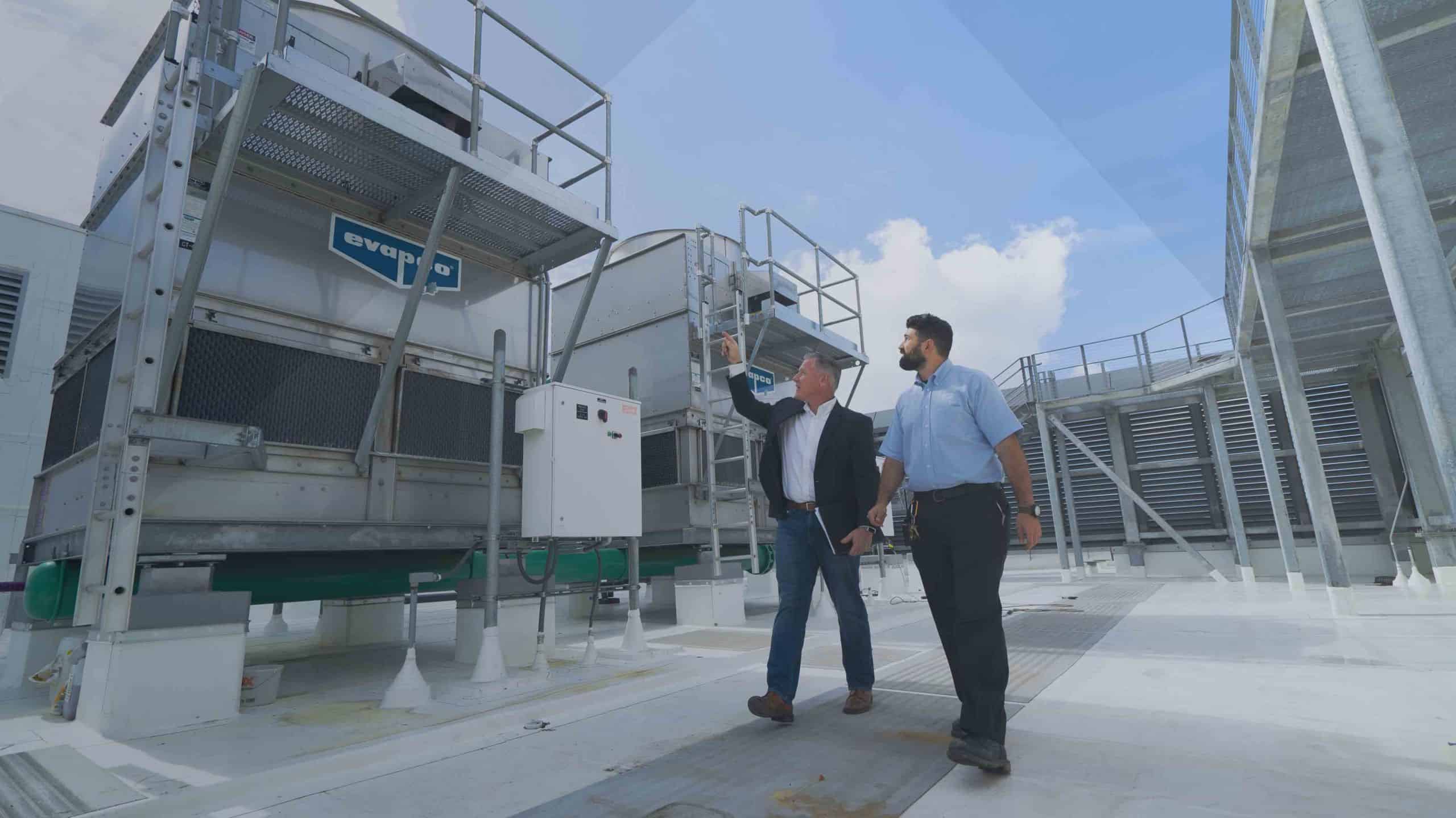 Servi-Tek engineers reviewing rooftop cooling-tower equipment during an energy benchmarking walk